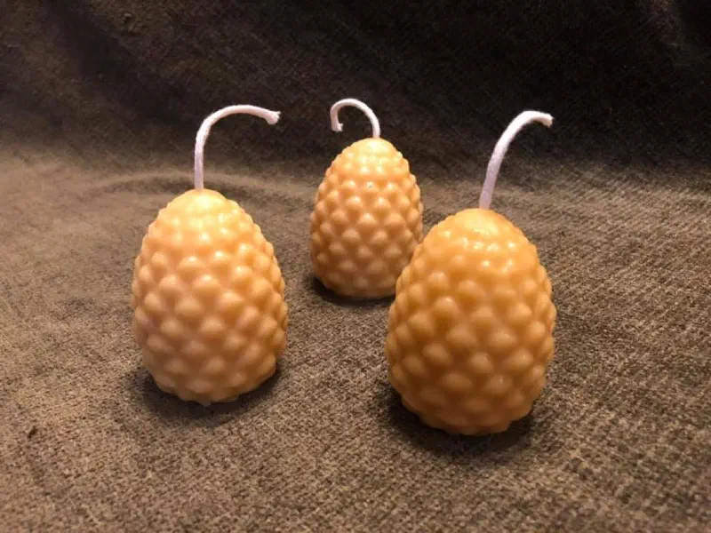 Three chunky beeswax candles shaped like pine cones