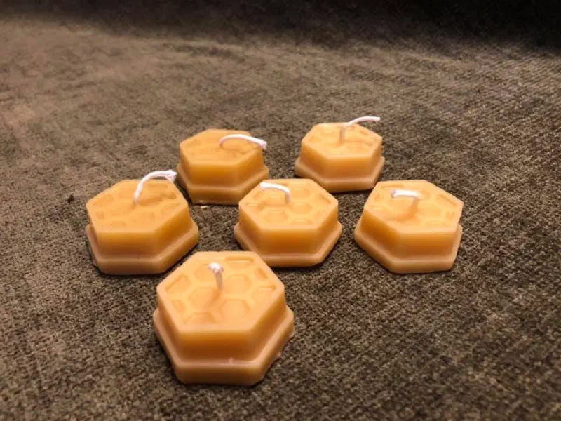 Six hexagonal beeswax tea lights with a honeycomb pattern on top