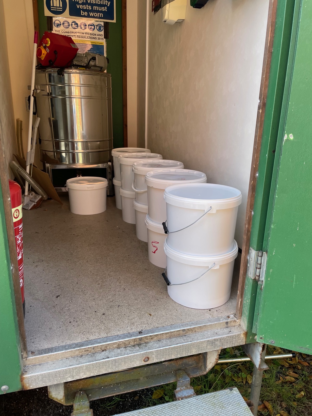 White honey buckets lined up inside the extraction facility at Broads Bee