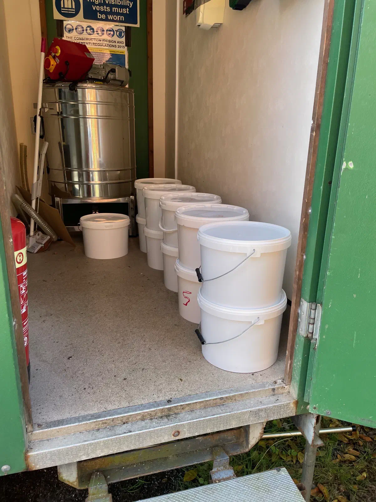 White honey buckets lined up inside the extraction facility at Broads Bee