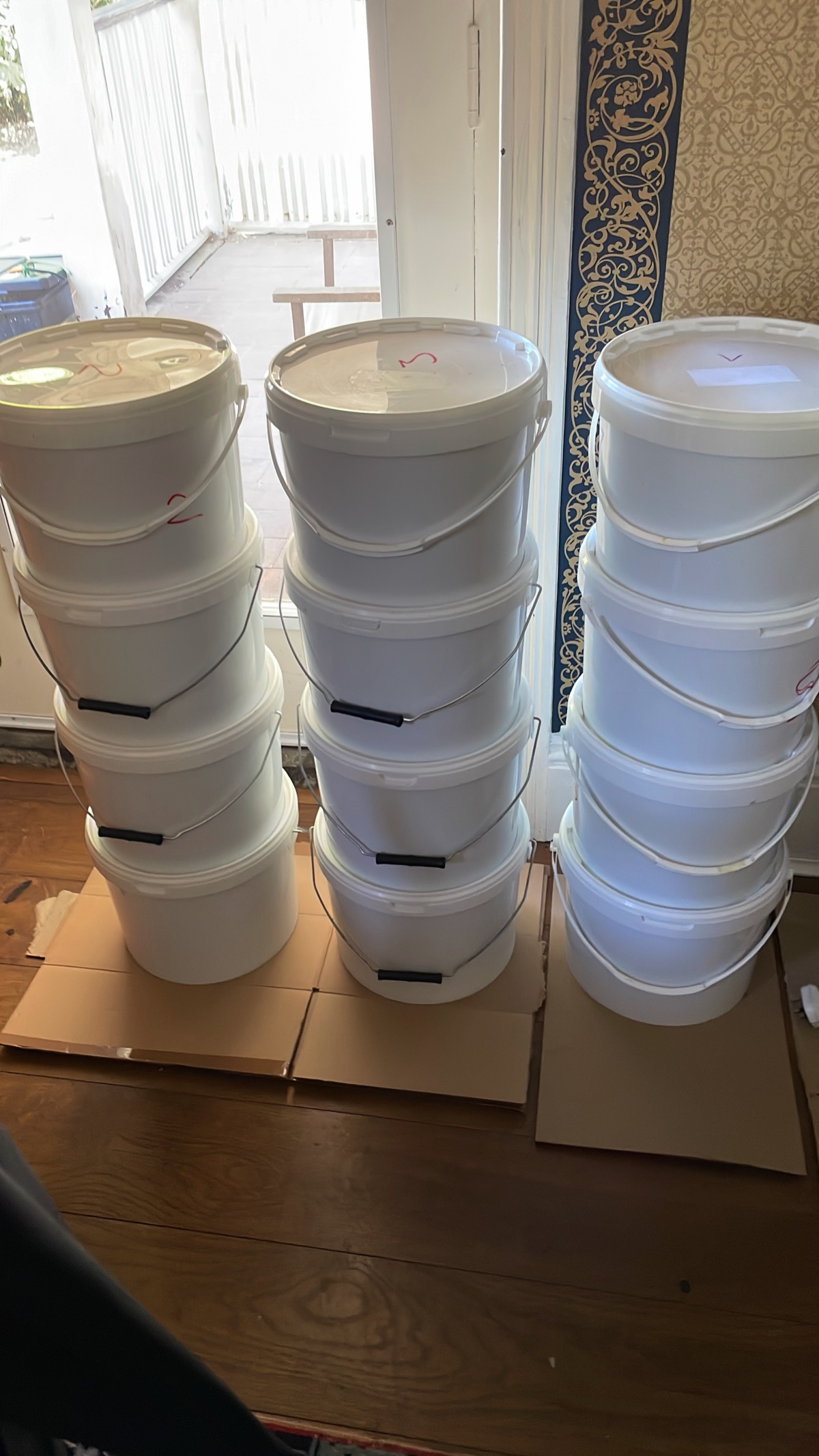 Tall stacks of white honey buckets stored indoors