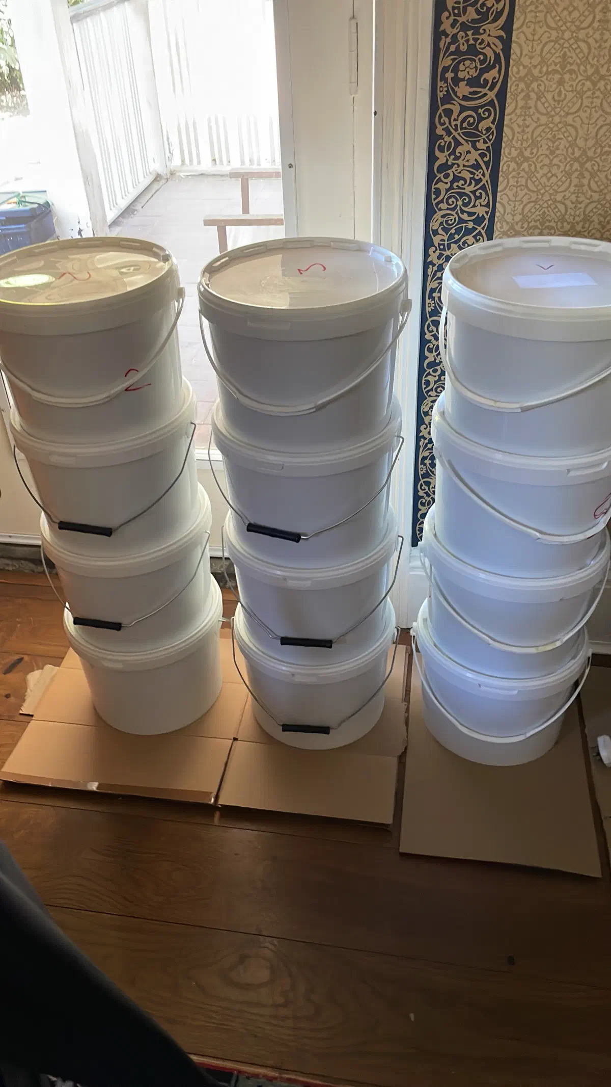 Tall stacks of white honey buckets stored indoors