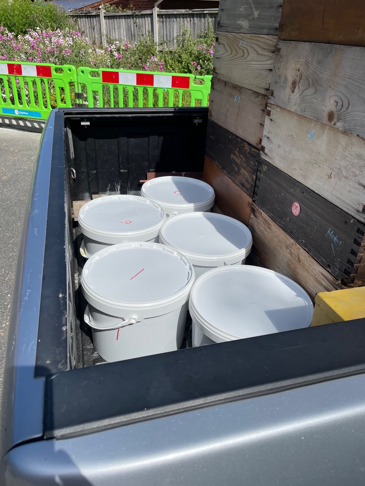 White honey buckets loaded in the bed of a pickup truck