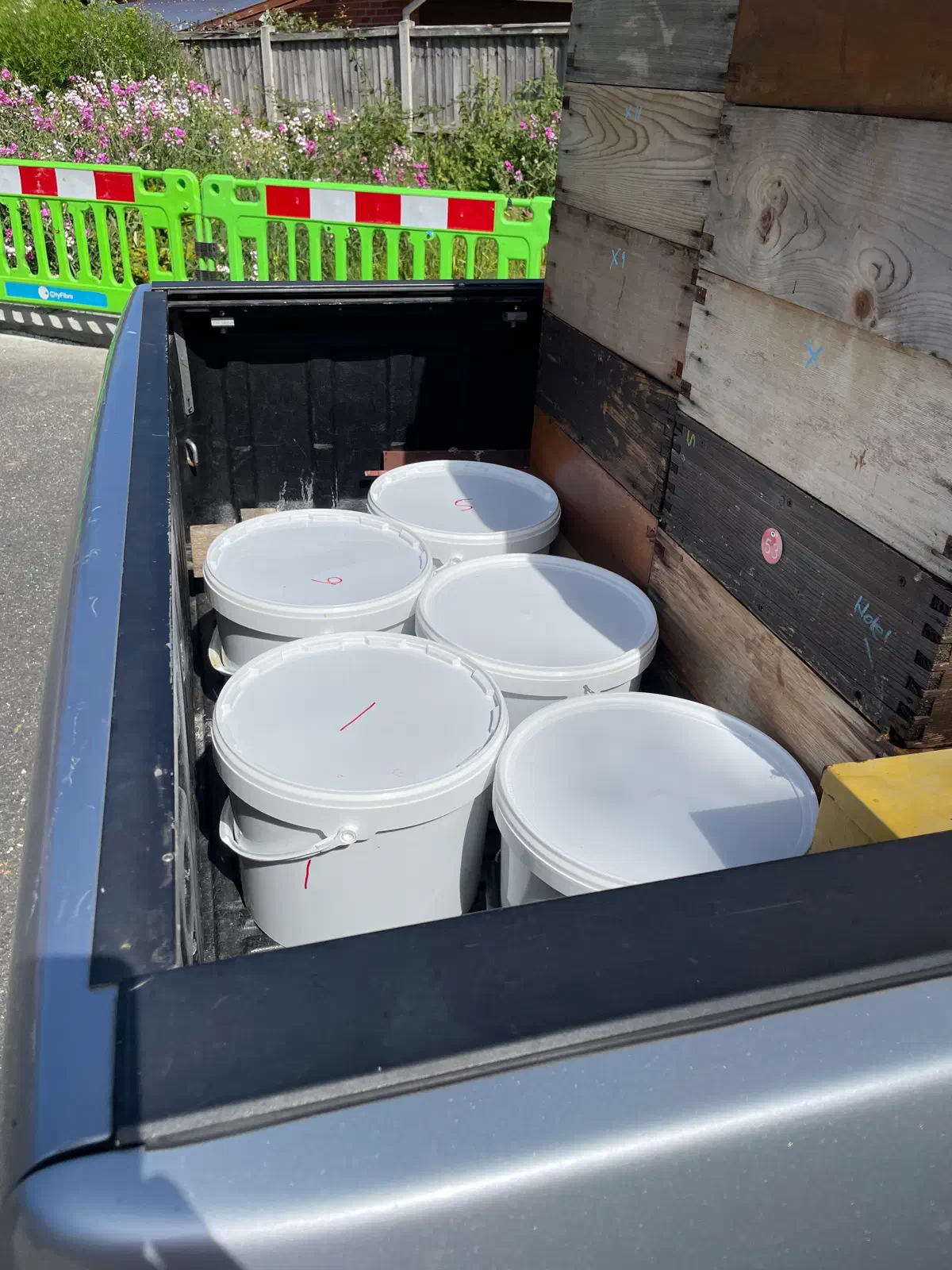 White honey buckets loaded in the bed of a pickup truck
