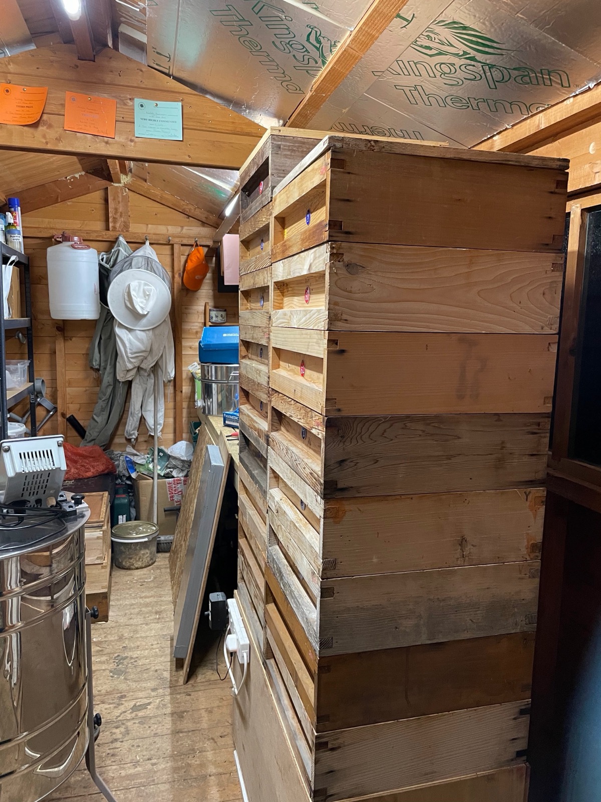 A tall stack of supers resting on top of the honey warmer in the honey house
